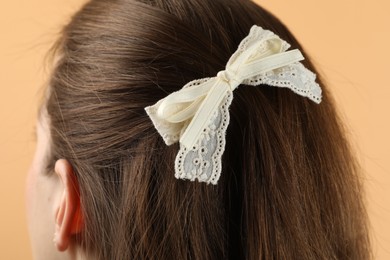 Photo of Woman with stylish hair bow on beige background, closeup