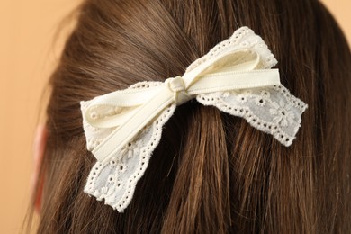 Photo of Woman with stylish hair bow on beige background, closeup