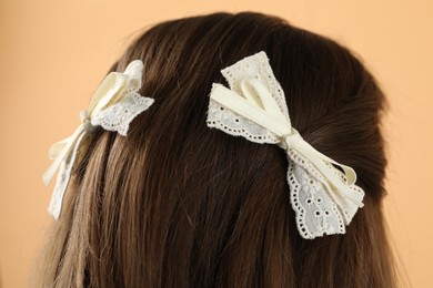 Woman with stylish hair bows on beige background, closeup