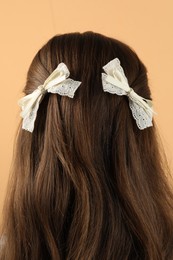 Woman with stylish hair bows on beige background, closeup