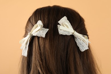 Photo of Woman with stylish hair bows on beige background, closeup