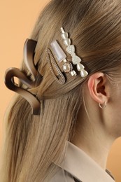 Woman with beautiful hair clips on beige background, closeup