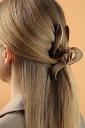 Woman with beautiful hair clip on beige background, closeup