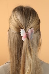 Woman with beautiful hair clip on beige background, back view