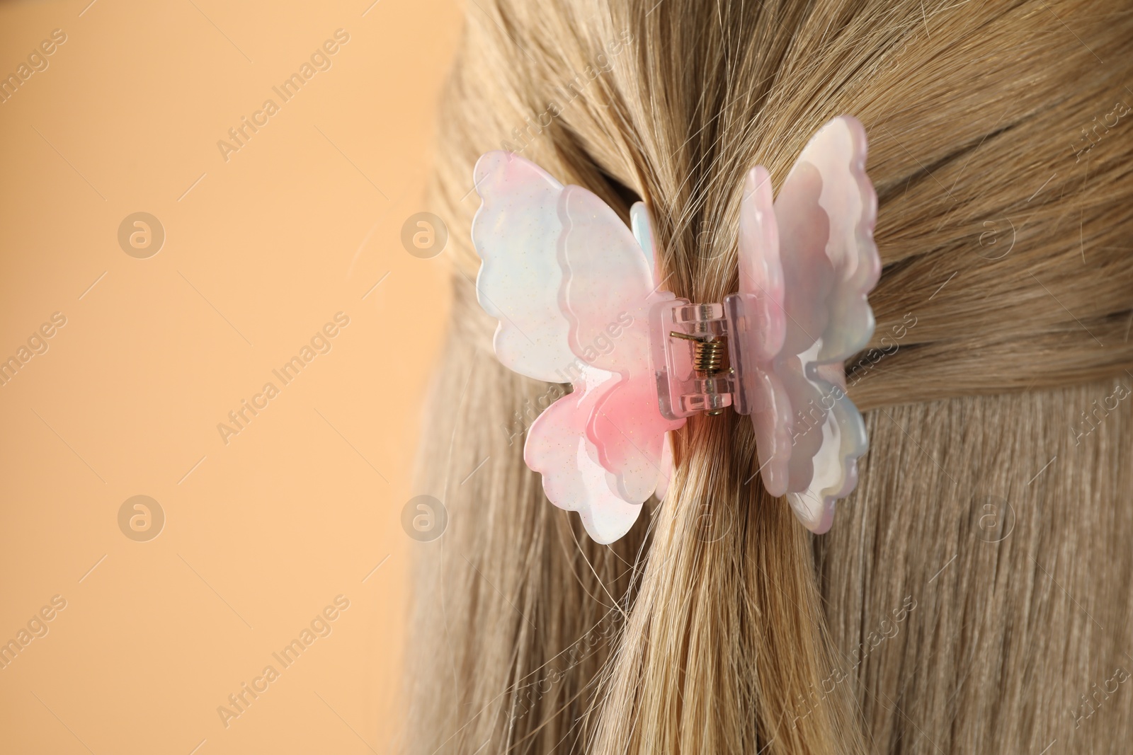 Photo of Woman with beautiful hair clip on beige background, closeup. Space for text