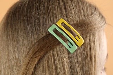 Woman with beautiful hair clips on beige background, closeup