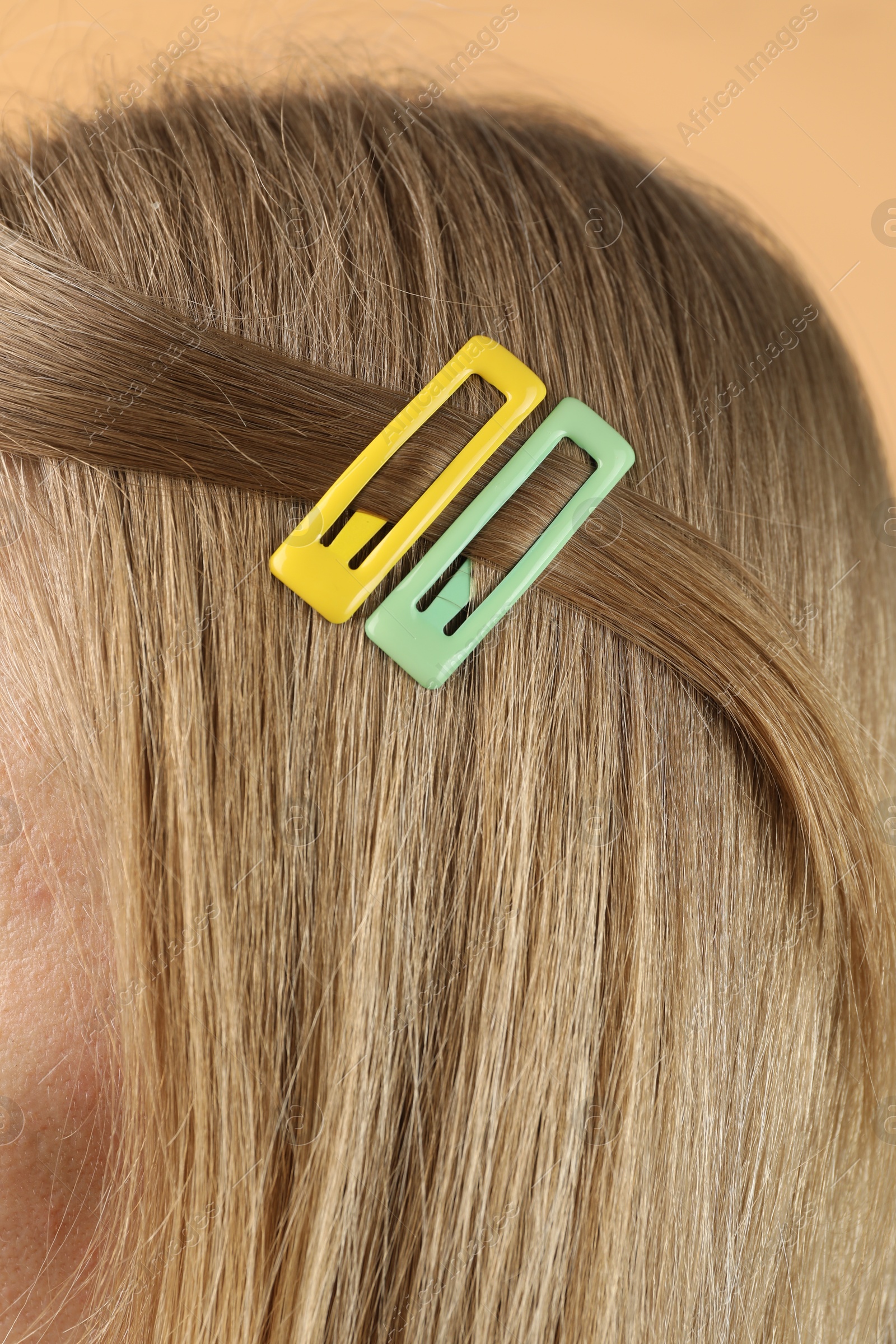 Photo of Woman with beautiful hair clips on beige background, closeup