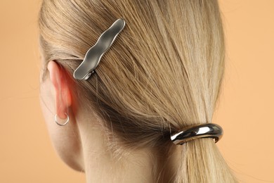 Woman with beautiful hair accessories on beige background, closeup