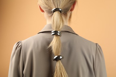 Photo of Woman with beautiful hair ties on beige background, back view