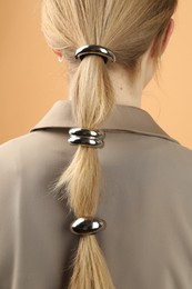 Woman with beautiful hair ties on beige background, back view