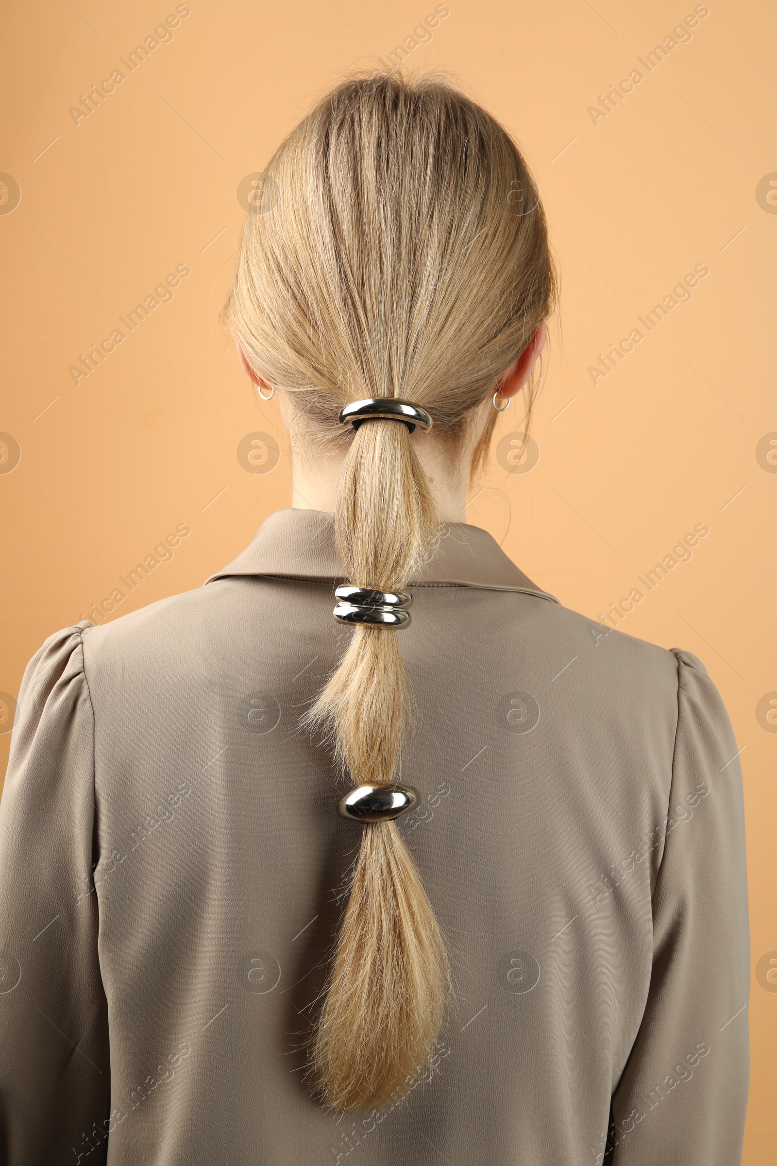 Photo of Woman with beautiful hair ties on beige background, back view