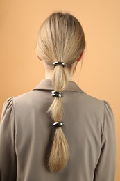 Photo of Woman with beautiful hair ties on beige background, back view