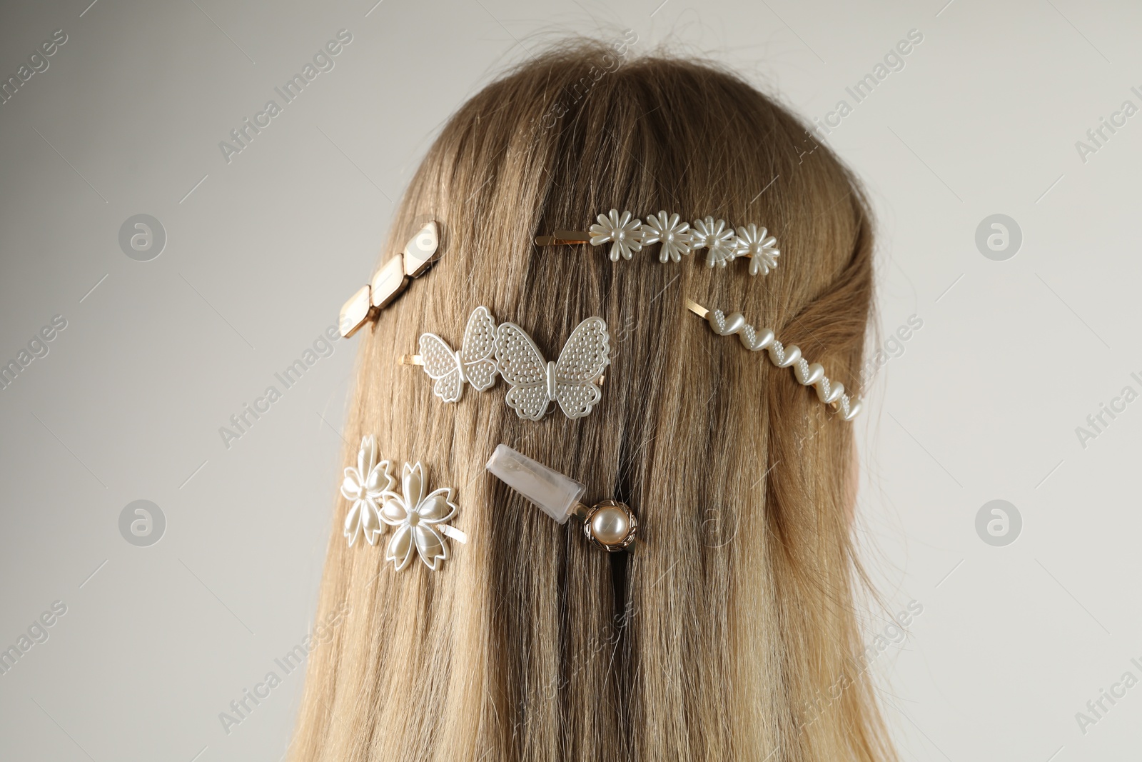 Photo of Woman with beautiful hair clips on light grey background, back view