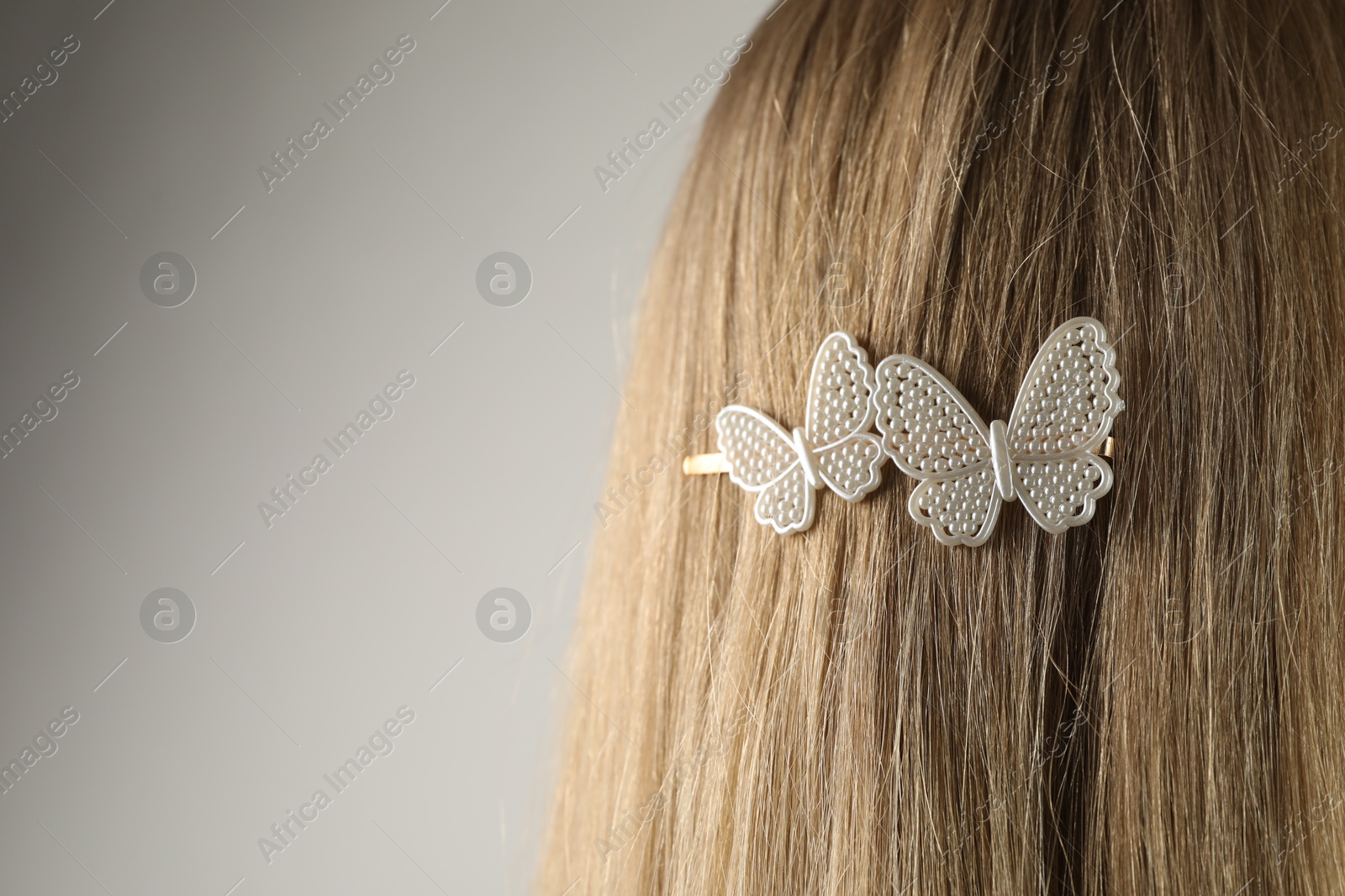 Photo of Woman with beautiful hair clip on light grey background, closeup. Space for text