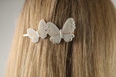 Woman with beautiful hair clip on light grey background, closeup