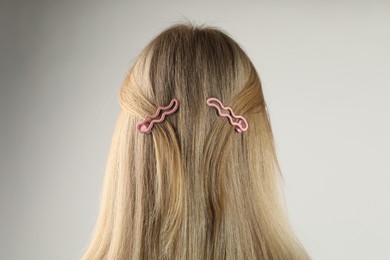 Photo of Woman with beautiful hair clips on light grey background, back view