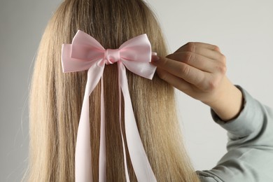 Photo of Woman with beautiful hair bow on light grey background, back view