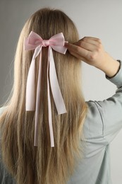 Photo of Woman with beautiful hair bow on light grey background, back view