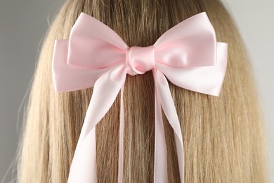 Woman with beautiful hair bow on light grey background, back view