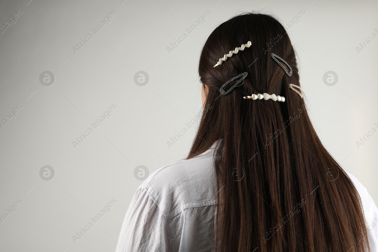 Photo of Woman with beautiful hair clips on light grey background, back view. Space for text