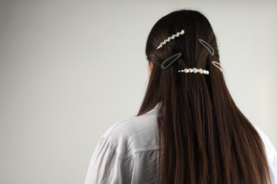 Woman with beautiful hair clips on light grey background, back view. Space for text