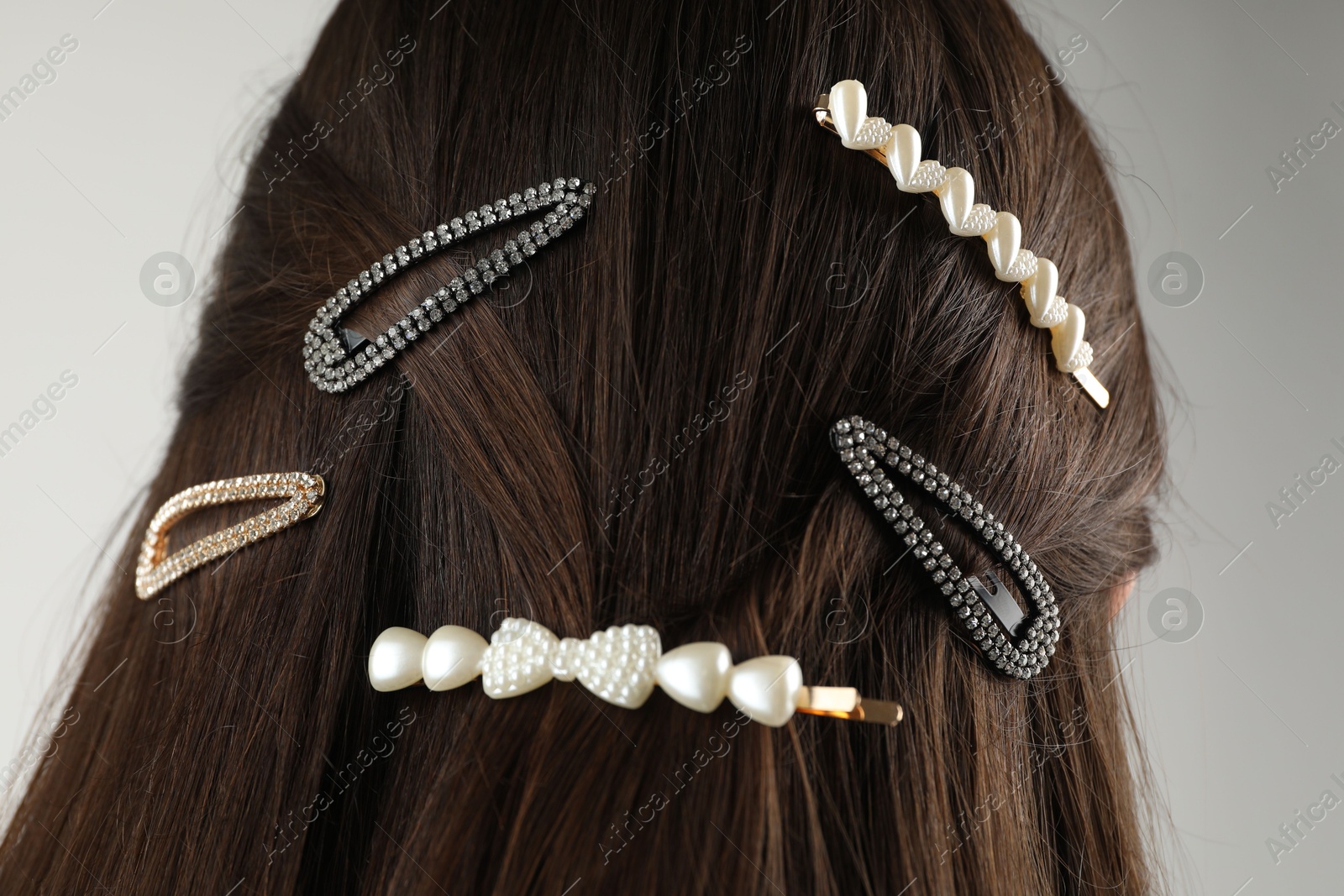 Photo of Woman with beautiful hair clips on light grey background, back view