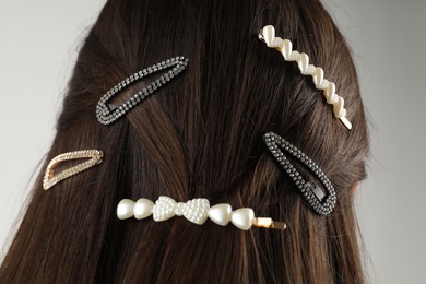 Woman with beautiful hair clips on light grey background, back view