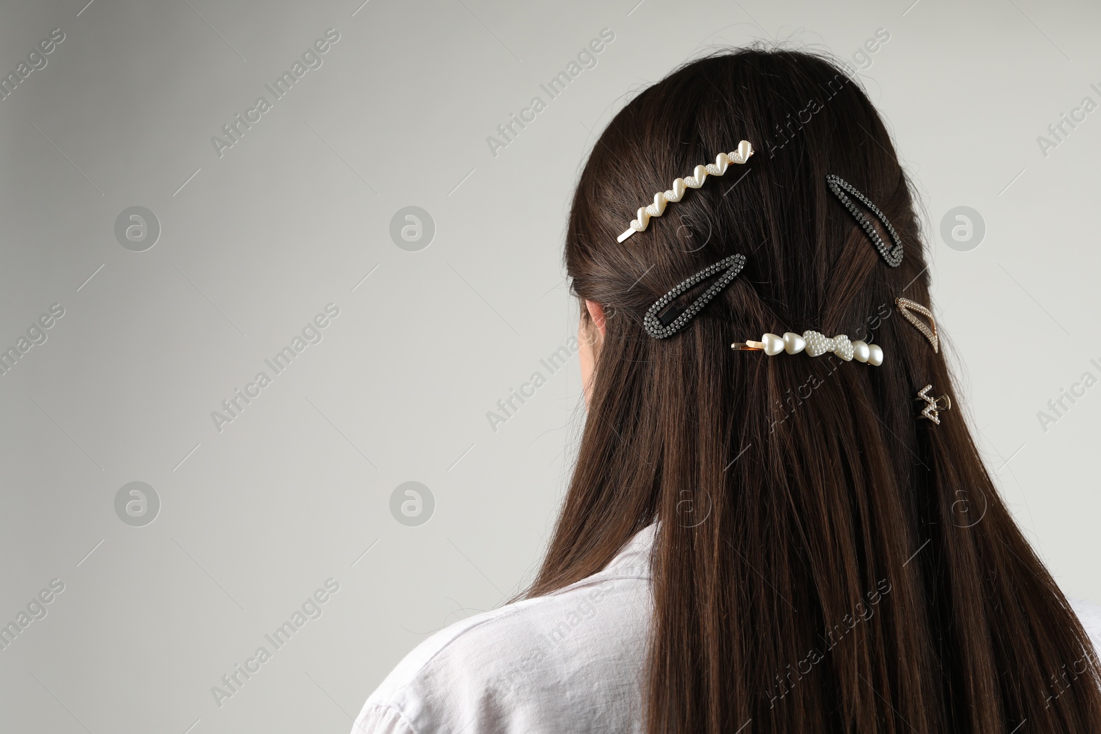 Photo of Woman with beautiful hair clips on light grey background, back view. Space for text