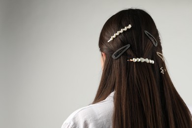 Photo of Woman with beautiful hair clips on light grey background, back view. Space for text