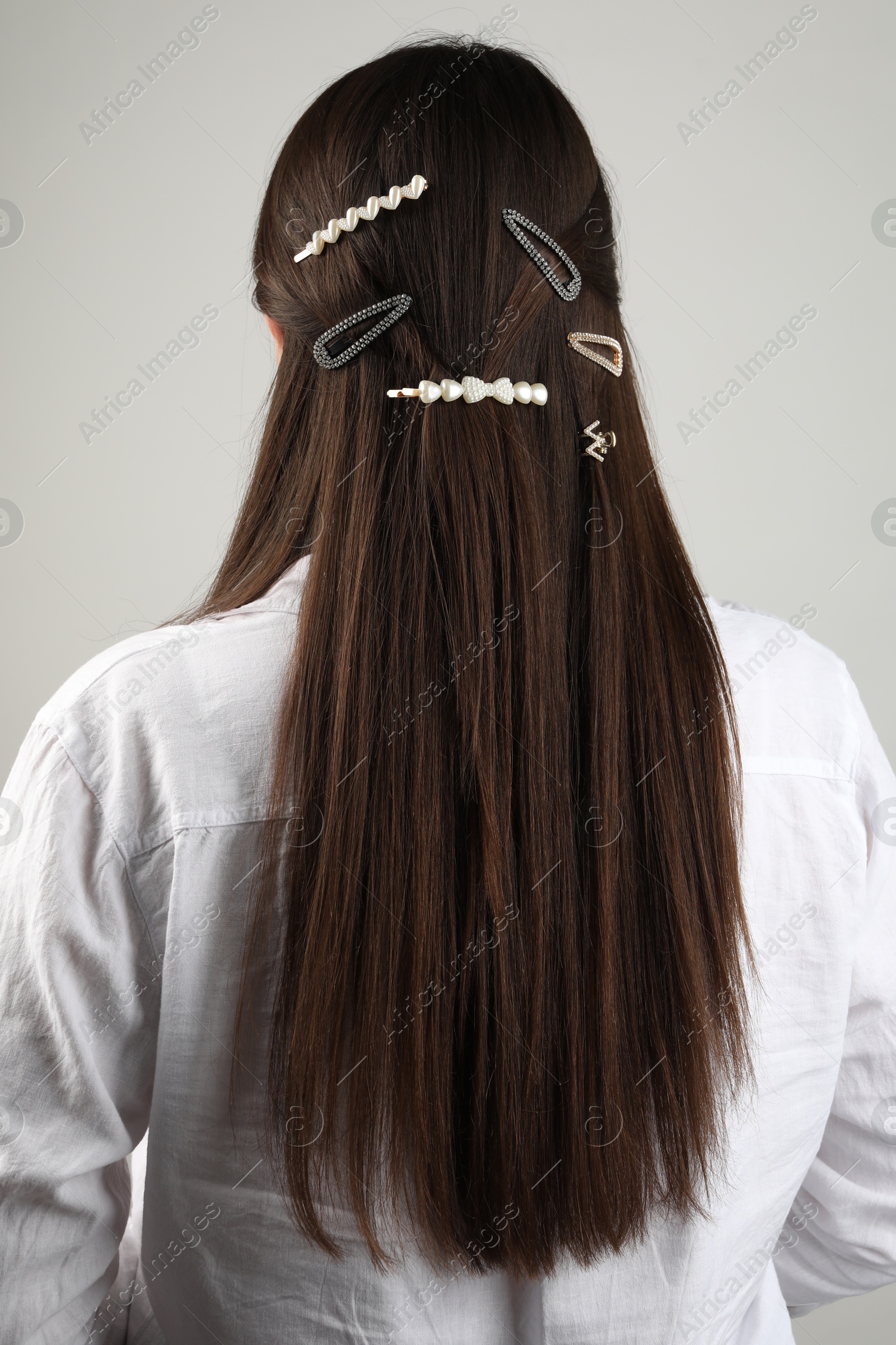 Photo of Woman with beautiful hair clips on light grey background, back view