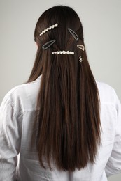 Woman with beautiful hair clips on light grey background, back view