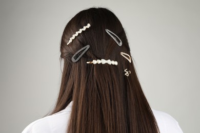 Photo of Woman with beautiful hair clips on light grey background, back view