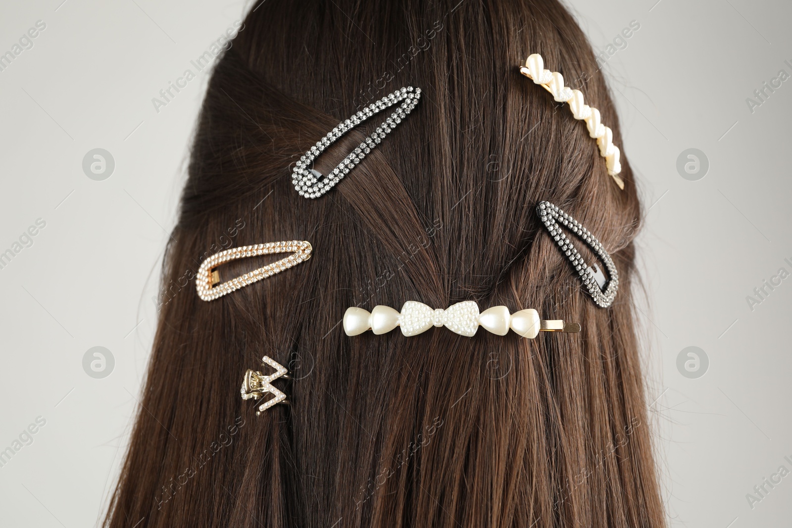 Photo of Woman with beautiful hair clips on light grey background, back view