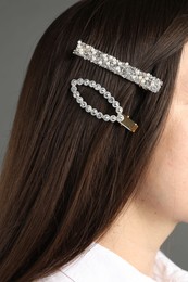 Woman with beautiful hair clips on grey background, closeup