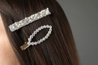 Woman with beautiful hair clips on grey background, closeup