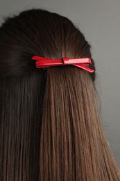 Woman with beautiful hair clip on grey background, back view