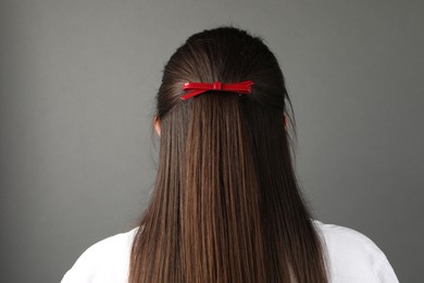 Woman with beautiful hair clip on grey background, back view