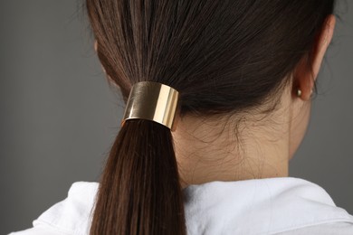 Woman with beautiful hair tie on grey background, back view