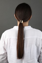 Photo of Woman with beautiful hair tie on grey background, back view