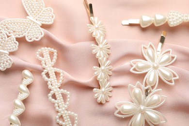 Beautiful hair clips on pink silk fabric, flat lay