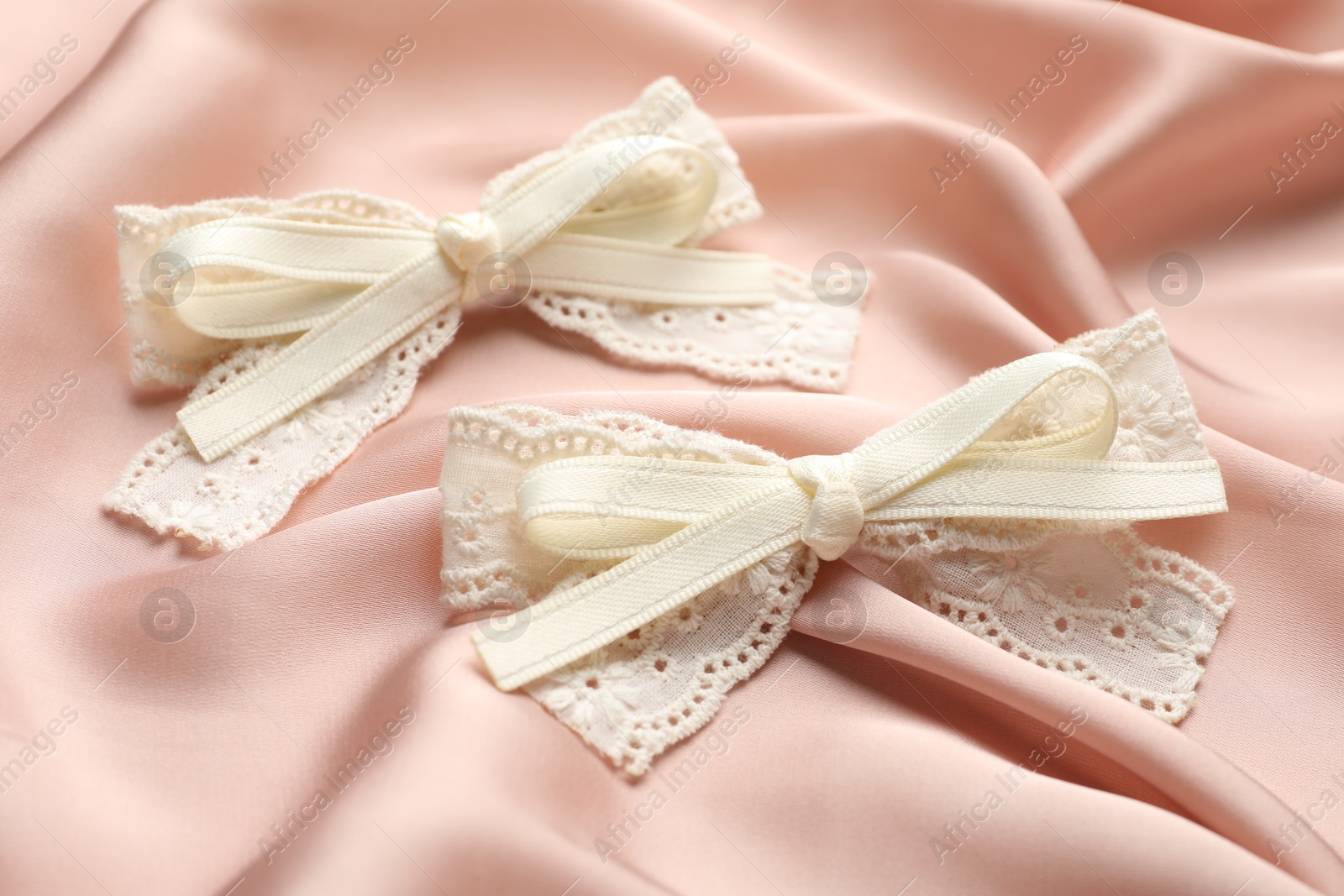 Photo of Beautiful hair bows on pink silk fabric, closeup