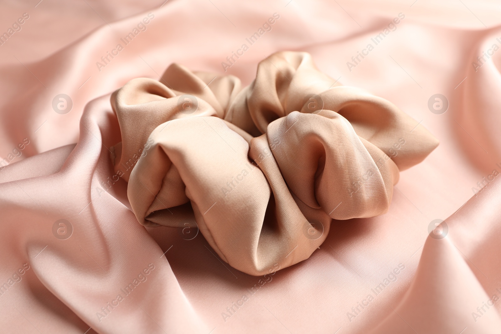 Photo of Hair scrunchie on pink silk fabric, closeup