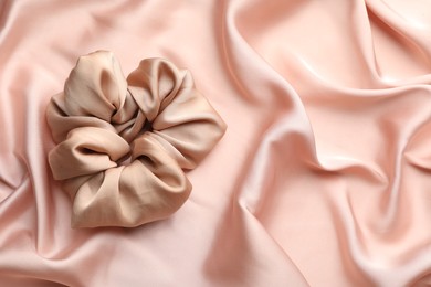 Photo of Hair scrunchie on pink silk fabric, top view. Space for text