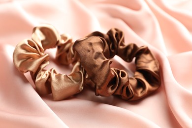 Photo of Hair scrunchies on pink silk fabric, closeup