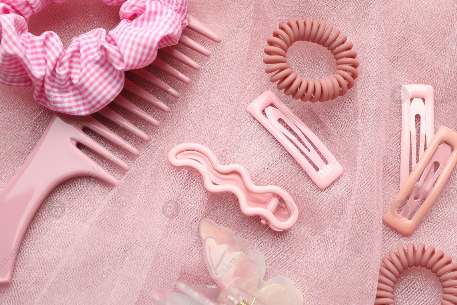 Photo of Beautiful hair accessories on pink tulle fabric, flat lay