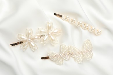 Beautiful hair clips on white silk fabric, flat lay