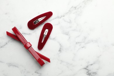 Photo of Beautiful hair clips on white marble table, flat lay. Space for text