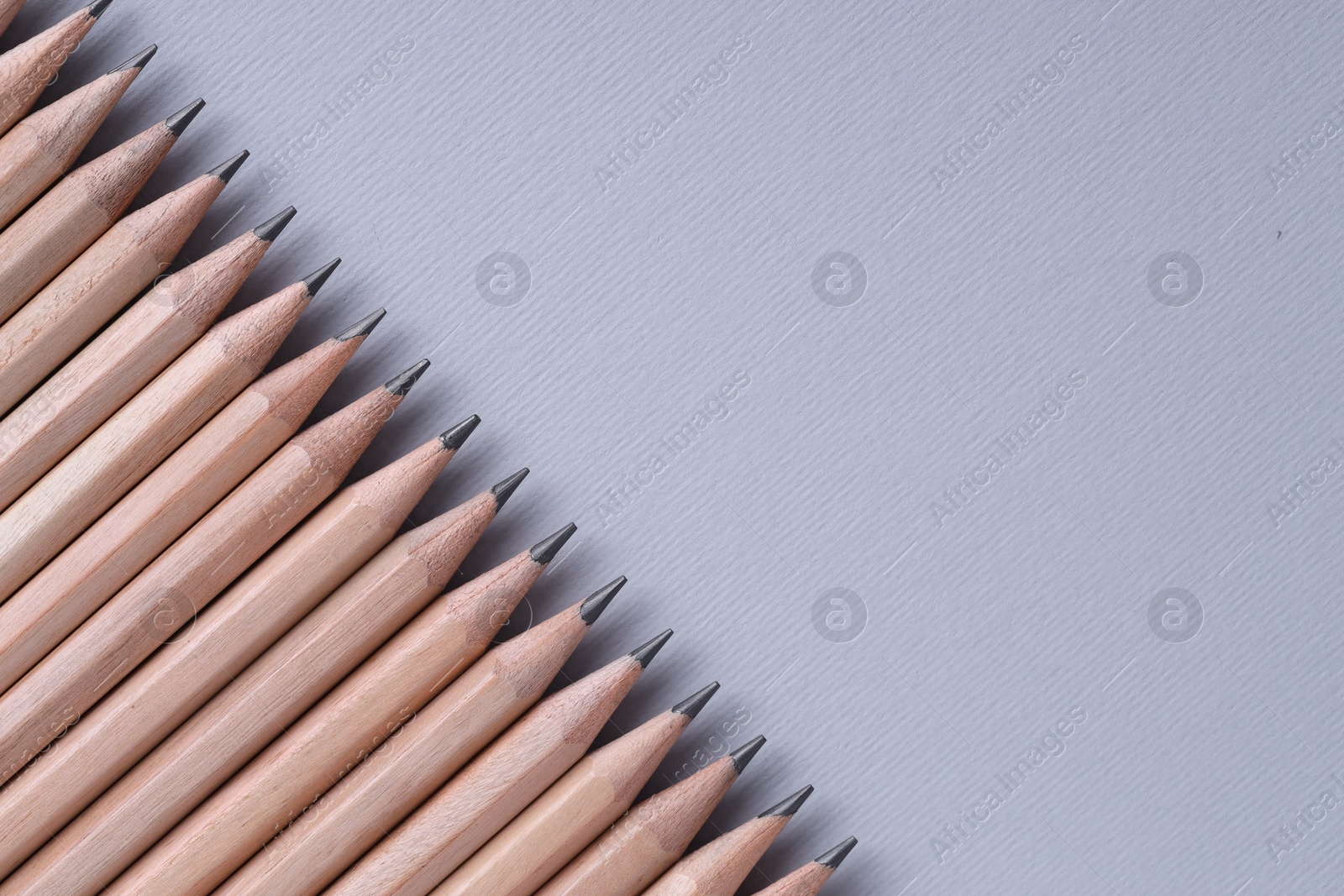 Photo of Many pencils on light grey background, top view. Space for text