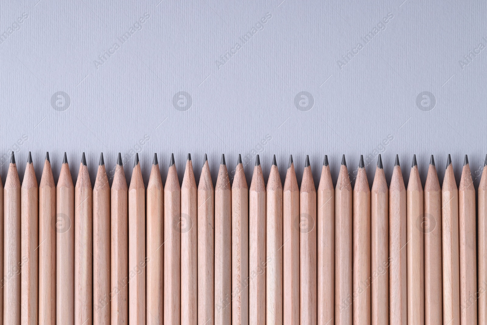 Photo of Many pencils on light grey background, top view. Space for text