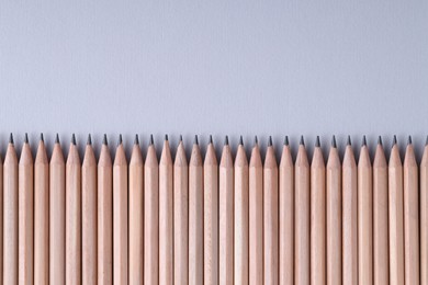 Photo of Many pencils on light grey background, top view. Space for text